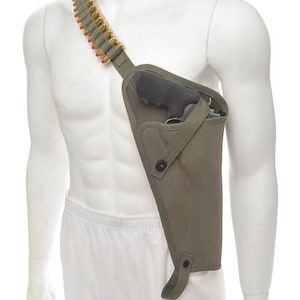 May include: An olive green shoulder holster with a black handgun inside. A bandolier of bullets is draped over the shoulder. The holster is made of canvas and has a button closure. The bullets are gold-colored.