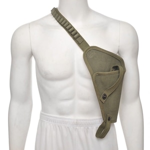 May include: Olive green shoulder holster with a strap and a series of loops. The holster has a triangular shape with a flap secured by a button. The strap is designed to be worn across the chest.