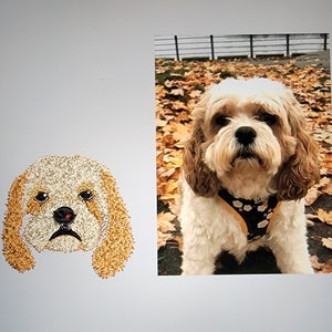 May include: An embroidered dog face with tan and white thread, next to a photo of a Cavalier King Charles Spaniel wearing a floral harness, set against a backdrop of autumn leaves. The embroidery captures the dog's likeness.