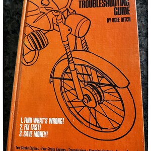 May include: An orange book titled "Chilton's Motorcycle Troubleshooting Guide" with a black line drawing of a motorcycle. The book cover includes the text: "Find What's Wrong! Fix Fast! Save Money!"