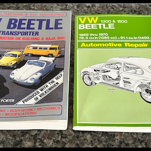 May include: Two vintage Volkswagen Beetle repair manuals. The left manual is a guide to purchase and DIY restoration of a VW Beetle and Transporter, including information on building a Baja Bug. The right manual is a Haynes Automotive Repair Manual for 1965-1970 VW Beetles with 1300 and 1500 cc engines.