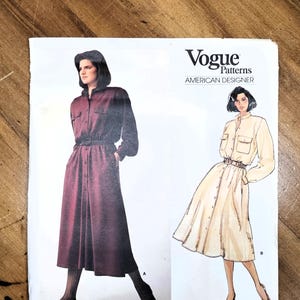 May include: Vogue Patterns American Designer sewing pattern featuring two dress designs. One dress is a long-sleeved, button-down style with a belt, and the other is a short-sleeved, button-down dress with a belt. The pattern is by Calvin Klein, pattern number 1442.