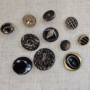 May include: Assortment of black and gold buttons with various designs, including a flower, a diamond, and a striped pattern.