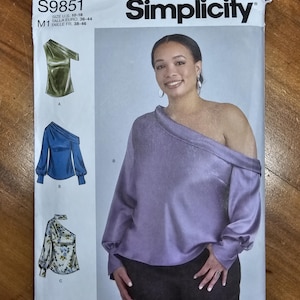 May include: Simplicity sewing pattern S9851. The pattern features designs for off-the-shoulder tops. The front of the pattern shows a woman wearing a lavender top. The pattern includes sizes 10-18.