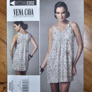 May include: A Vogue Patterns sewing pattern envelope for a sleeveless dress, labeled Vena Cava Cutting Edge V1229. The front displays a white dress with a grey patterned print, featuring a gathered bodice, a V-neckline, and a loose, short silhouette.