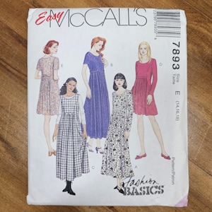 May include: A vintage McCall's sewing pattern featuring illustrations of dresses. The pattern packet is white with the text "Easy McCall's" in red and the number "7893". The "Fashion Basics" logo is visible.