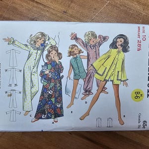 May include: A vintage Butterick sewing pattern for children's and girls' sleepwear, size 10, featuring illustrations of various pajama styles. The pattern includes a long robe, a jumpsuit, and shorts sets. The cover is white with illustrations in color.