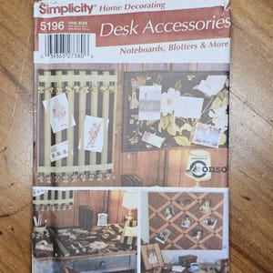 May include: A Simplicity Home Decorating pattern for desk accessories, including note boards and blotters. The cover features images of various desk decor items, such as a memo board with photos and a floral-patterned desk blotter.