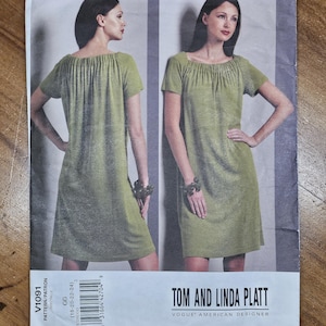 May include: A Vogue American Designer sewing pattern envelope for V1091 by Tom and Linda Platt. The front shows a light green knee-length dress with short sleeves and a gathered neckline, displayed from both the front and back views on a model.