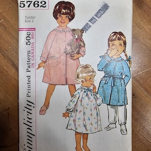 May include: Vintage Simplicity pattern 5762 for a toddler size 2. The cover features illustrations of three young children in dresses and pajamas. The pattern includes the text "Printed Pattern 50c in Canada 60c".