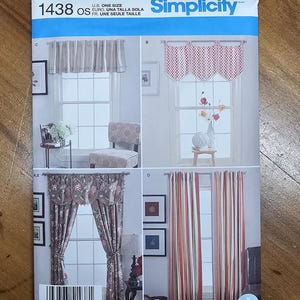 May include: Simplicity sewing pattern 1438 OS featuring four window treatment designs. The pattern includes instructions for valances and curtains in various styles. The package displays the text "U.S. ONE SIZE" and "Designed and printed in the USA."