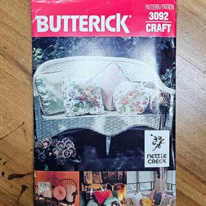 May include: A Butterick craft pattern, number 3092, featuring a wicker sofa with floral pillows. The cover is red with the Butterick logo and the words "Pattern/Patron" and "Craft". The Nettle Creek logo is also visible.