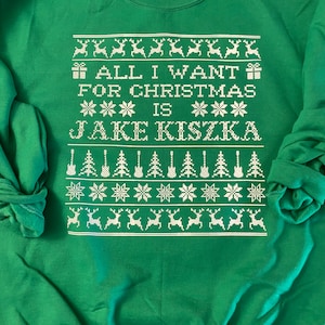 May include: Green Christmas sweater with white text that reads "All I want for Christmas is Jake Kiszka" with a white snowflake and reindeer pattern.