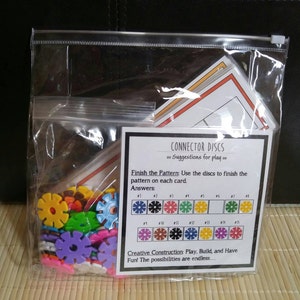 May include: A clear plastic bag containing a set of colorful plastic connector discs. The bag also includes instructions for playing a pattern game with the discs. The instructions include a chart with different color and shape combinations.
