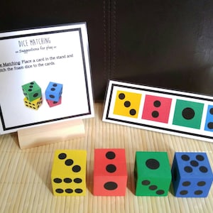 May include: A set of four foam dice with different numbers of black dots on each side. The dice are yellow, red, green, and blue. A card with four squares showing the same number of dots as the dice is also included. The card says "Dice Matching" and has instructions for playing the game.