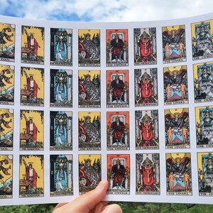 May include: A sheet of paper with 25 tarot cards printed on it. The cards are arranged in five rows of five cards each. Each card features a different tarot card image, including The Fool, The Magician, The Empress, The Emperor, The Hierophant, The Lovers, and The Chariot.