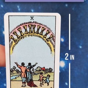May include: A tarot card sticker featuring the Ten of Cups card from a Rider-Waite style deck. The card depicts a family of four standing in a field with a rainbow arch above them. The sticker is 1.25 inches wide and 2 inches tall.