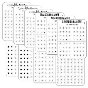May include: A collection of white sticker sheets labeled Armadillo Amore, featuring rows of small black circular icons. The designs include zodiac symbols, moon phases, planetary glyphs, prescription symbols, and various geometric shapes in a grid layout.