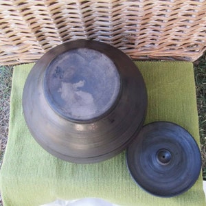 May include: A black ceramic pot with a lid. The pot is round and has a smooth surface. The lid has a small hole in the center.