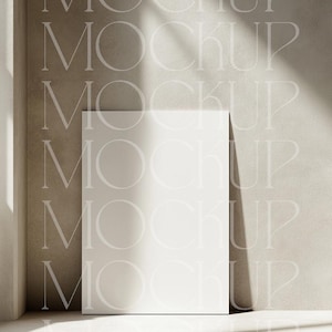 May include: A white blank poster mockup on a light brown textured wall with a shadow from a window. The poster is standing on a light brown floor.