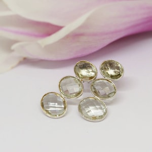May include: A pair of silver earrings with five clear faceted gemstones. The gemstones are arranged in a staggered pattern.