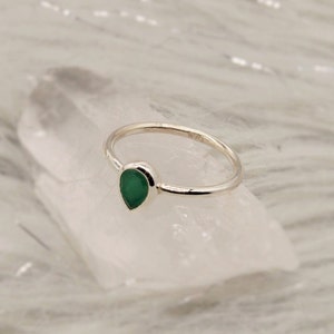 May include: A silver ring with a teardrop-shaped green gemstone.
