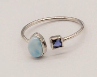 Könnte beinhalten: Ein silberner Ring mit einem tropfenförmigen blauen Edelstein und einem quadratischen violetten Edelstein.