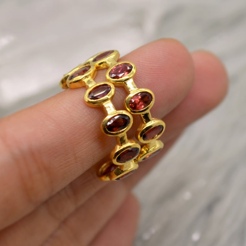 May include: Gold ring with three rows of oval-shaped red gemstones.