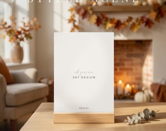 May include: A vertical white rectangular card held in a light-toned wooden stand. The card features the text "add your own 5X7 DESIGN" and "DE-DI-TU" printed in black. The stand is positioned on a matching light-toned wooden surface.