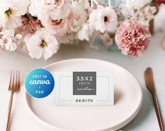 May include: A place card mockup on a pink plate with a rose gold fork and knife. The card is 3.5 x 2 inches and has the text "mockup" on it. The background features a floral arrangement with pink and white flowers.