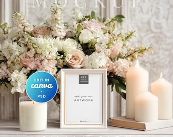 May include: A mockup featuring a white framed 5x7 inch artwork with gold trim, surrounded by a floral arrangement of pink and white roses. The scene includes lit candles and the text "add your own artwork".