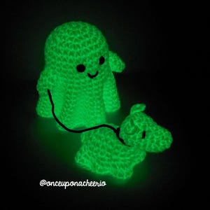 May include: A green crocheted ghost holding a leash attached to a green crocheted dog. Both glow in the dark.