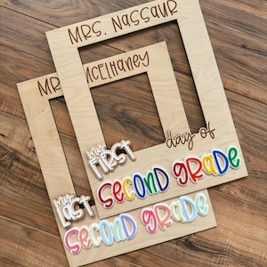 May include: Two wooden photo frames with engraved text: "MRS. NASSAUR" and "MR. MCELHANEY". Below, colourful text reads "My First Second Grade" and "My Last Second Grade".