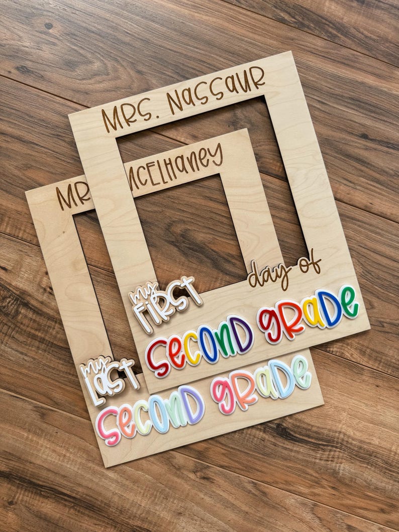 May include: Two wooden photo frames with engraved text: "MRS. NASSAUR" and "MR. MCELHANEY". Below, colourful text reads "My First Second Grade" and "My Last Second Grade".