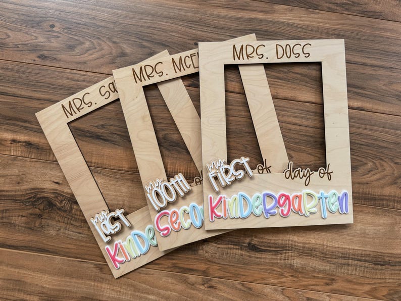 May include: Wooden photo frames with the text "MRS. S", "MRS. MCE", and "MRS. DOSS" engraved at the top. The frames have attached text that reads "My Last", "100th", and "First day of Kindergarten" in colourful letters.