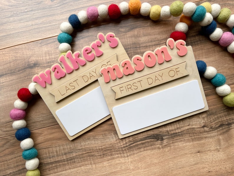 K&ouml;nnte beinhalten: Zwei Holzschildchen mit rosa Beschriftung. Das obere Schild sagt "Walker's Last Day Of" und das untere Schild sagt "Mason's First Day Of". Beide Schilder haben einen leeren Platz zum Schreiben.