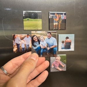 May include: A collection of square photo magnets, each displaying a different family photo. The magnets are attached to a metallic surface. One magnet is being held by a hand, showcasing a family portrait.