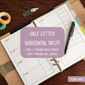 May include: A planner with a light brown leather cover, open to a lined page with a pen. The page has the text "HALF LETTER HORIZONTAL WO2P" and "LINED, 3 TRACKING BOXES, MONDAY START, PRINTABLE PDF, UNDATED". Also visible are washi tape and a paper clip.
