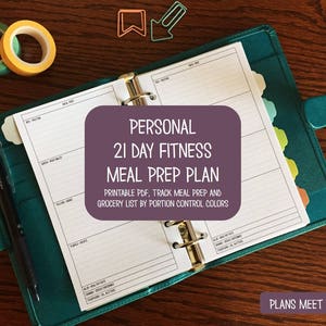 Puede incluir: Un archivador turquesa con un plan de preparación de comidas, abierto en una página en blanco. El plan está etiquetado como "Personal 21 Day Fitness Meal Prep Plan". Incluye un bolígrafo, cinta washi y clips. El texto "Plans Meet Paper" está en la parte inferior.