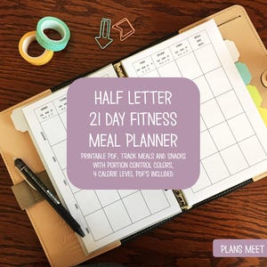 Könnte beinhalten: Ein beiger Lederplaner mit einem 21-Tage-Fitness-Essensplaner. Der Planer enthält einen Stift, Washi-Tape und Büroklammern. Der Essensplaner trägt die Aufschrift "HALF LETTER 21 DAY FITNESS MEAL PLANNER". Der Text "PLANS MEET PAPER" ist ebenfalls sichtbar.