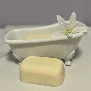 May include: A white porcelain bathtub with a white flower on top and a bar of soap sitting in front of it.