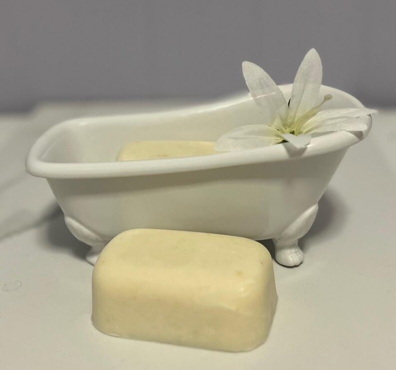May include: A white porcelain bathtub with a white flower on top and a bar of soap sitting in front of it.