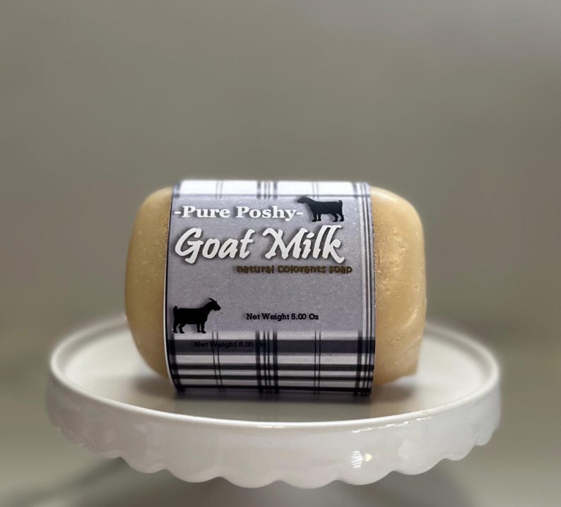 May include: A bar of goat milk soap with a white and black plaid label that reads "Pure Poshy - Goat Milk - Natural Colorants Soap" and "Net Weight 5.00 Oz".