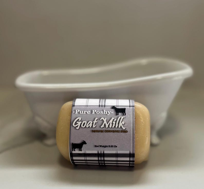 May include: A bar of goat milk soap with a black and white plaid label that reads "Pure Poshy - Goat Milk - Natural Colorants Soap - Net Weight 5.00 Oz."