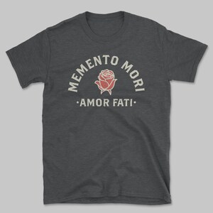 Op de afbeelding: Donkergrijs t-shirt met een vintage print. Het ontwerp toont de woorden "MEMENTO MORI" boven een rode rozenillustratie en "AMOR FATI" eronder. Het shirt is gemaakt van een zacht materiaal.