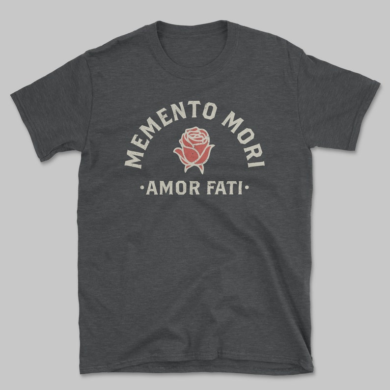 Op de afbeelding: Donkergrijs t-shirt met een vintage print. Het ontwerp toont de woorden "MEMENTO MORI" boven een rode rozenillustratie en "AMOR FATI" eronder. Het shirt is gemaakt van een zacht materiaal.