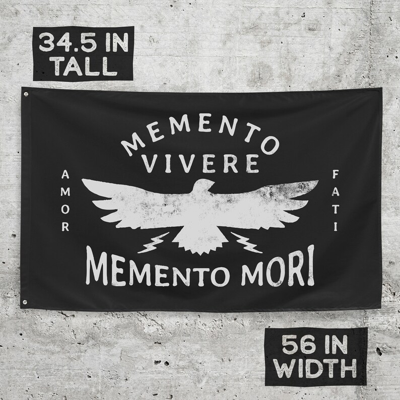 May include: Black flag with white distressed text and graphic. The flag reads "Memento Vivere" above a bird graphic, with "Amor" on the left and "Fati" on the right. Below the bird is "Memento Mori". The flag is 34.5 inches tall and 56 inches wide.