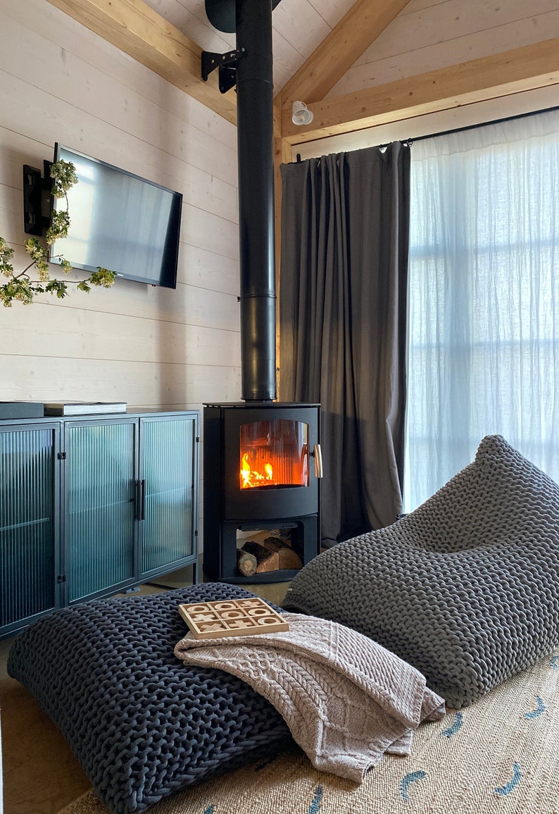 giant beanbag and floor cushion in front of a wood burner fire in a neutral living room home with earthy tones