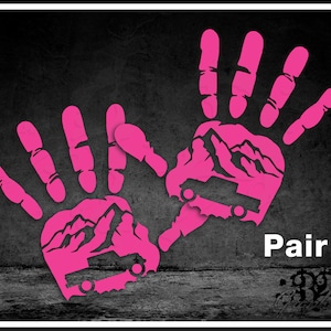 以下が含まれることがあります： ピンク色の手形グラフィック。山脈のデザインと白い文字で「Pair」と書かれています。背景は、テクスチャ加工されたグレーと黒のデザインです。