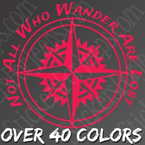 Könnte beinhalten: Ein rotes Kompassrosen-Design mit dem Text "NOT ALL WHO WANDER ARE LOST" und "OVER 40 COLORS" auf grauem Hintergrund. Die Kompassrose ist ein Navigationswerkzeug, das oft auf Reisen und bei der Erkundung verwendet wird.